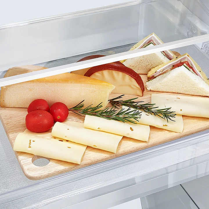 나무 도마 위에 다양한 음식이 놓여 있습니다. 슬라이스 치즈와 둥근 치즈, 샌드위치 조각이 있으며, 방울토마토와 허브 가지가 함께 있습니다. 