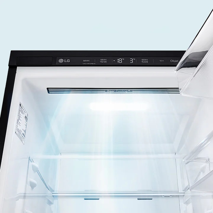 LG 냉장고의 내부를 보여주고 있습니다. 냉장고 문이 열려 있으며, 내부에는 선반이 보입니다. Door Cooling+라는 텍스트가 있습니다. 냉장고의 디스플레이 패널에는 냉동실, 냉장실, -18&deg;C, 3&deg;C라는 텍스트가 표시되어 있습니다. 냉장고 내부는 밝은 조명으로 비추어져 있습니다.
