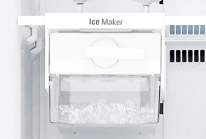 Ice Maker라는 텍스트가 적힌 얼음 제조기가 보입니다. 투명한 용기 안에 얼음이 담겨 있으며, 기기는 깔끔한 흰색으로 디자인되어 있습니다. 주변은 주방 기기의 일부분으로 보이는 배경입니다.